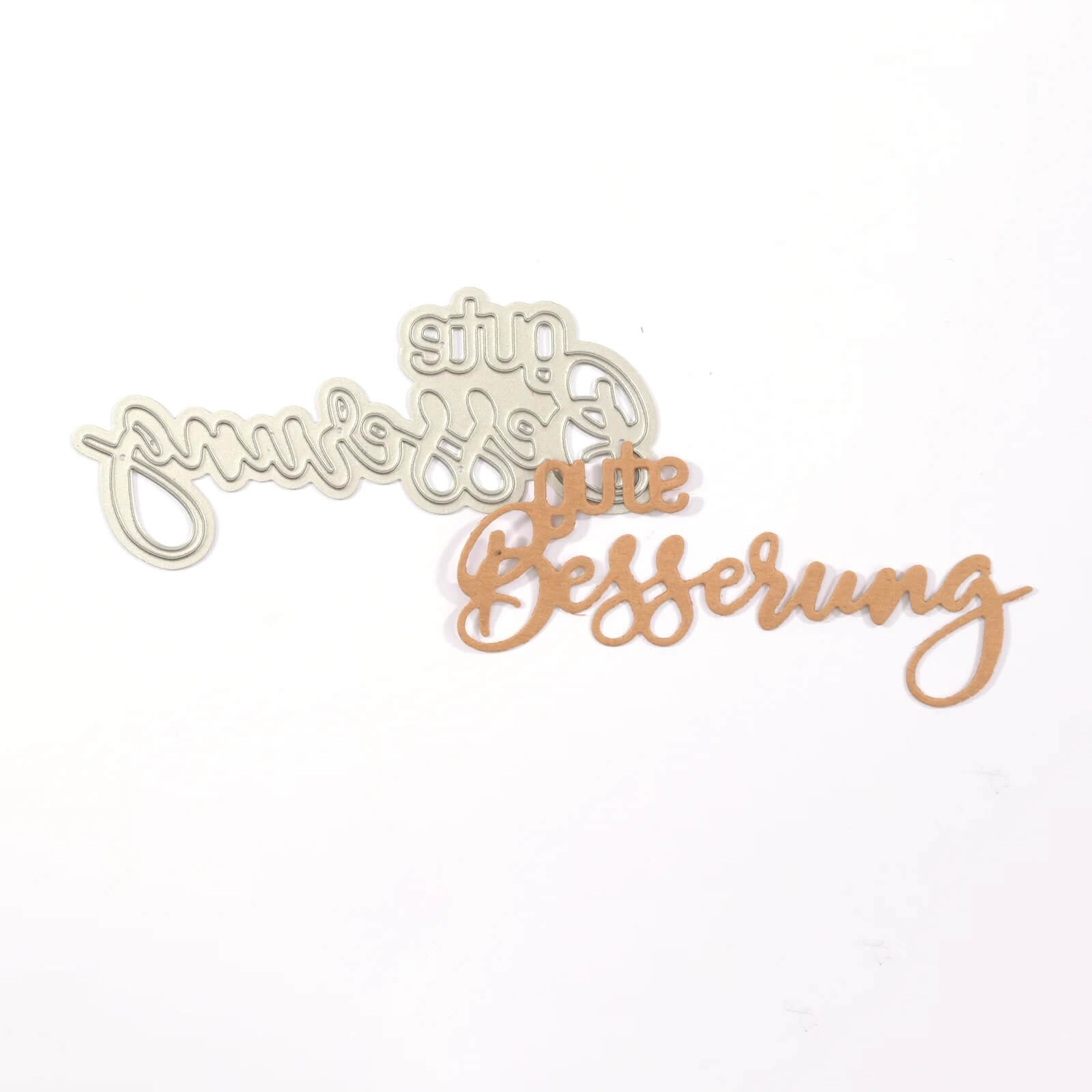 Die Mundart Stempel - Stanzschablone "gute Besserung" zeigt eine 4 x 9 cm große Metallstanze mit dem deutschen Text "gute Besserung" in Schreibschrift auf weißem Hintergrund. Marke: Mundart Stempel.