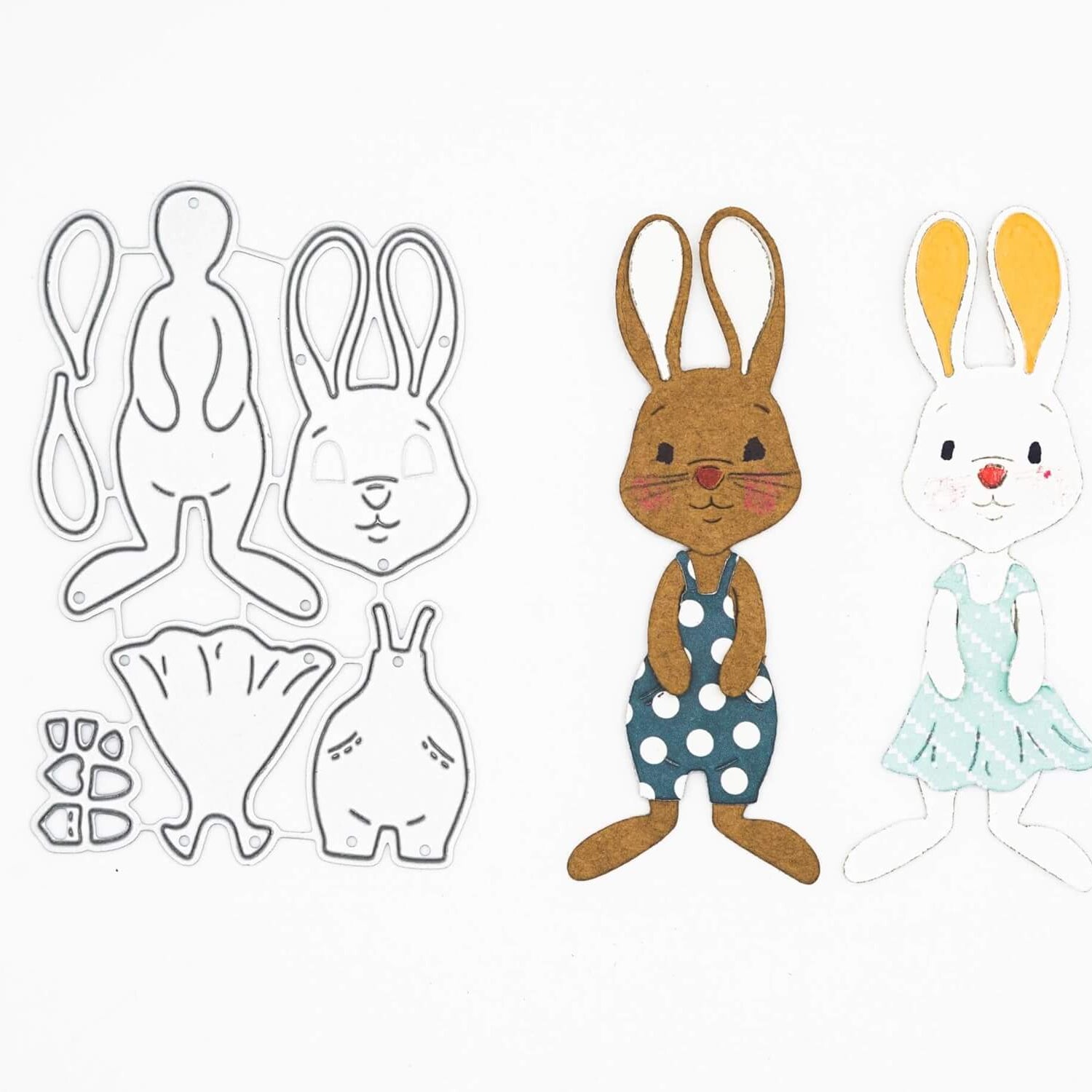 Die Stanzschablone: Bastelset Osterhase von Stanzenshop.de enthält Stanzformen in Hasenform aus Metall und zwei zusammengesetzte Papierhasen - braun mit gepunktetem Kleid und weiß mit blauem Kleid - ideal für Scrapbooking, dargestellt auf weißem Hintergrund.
