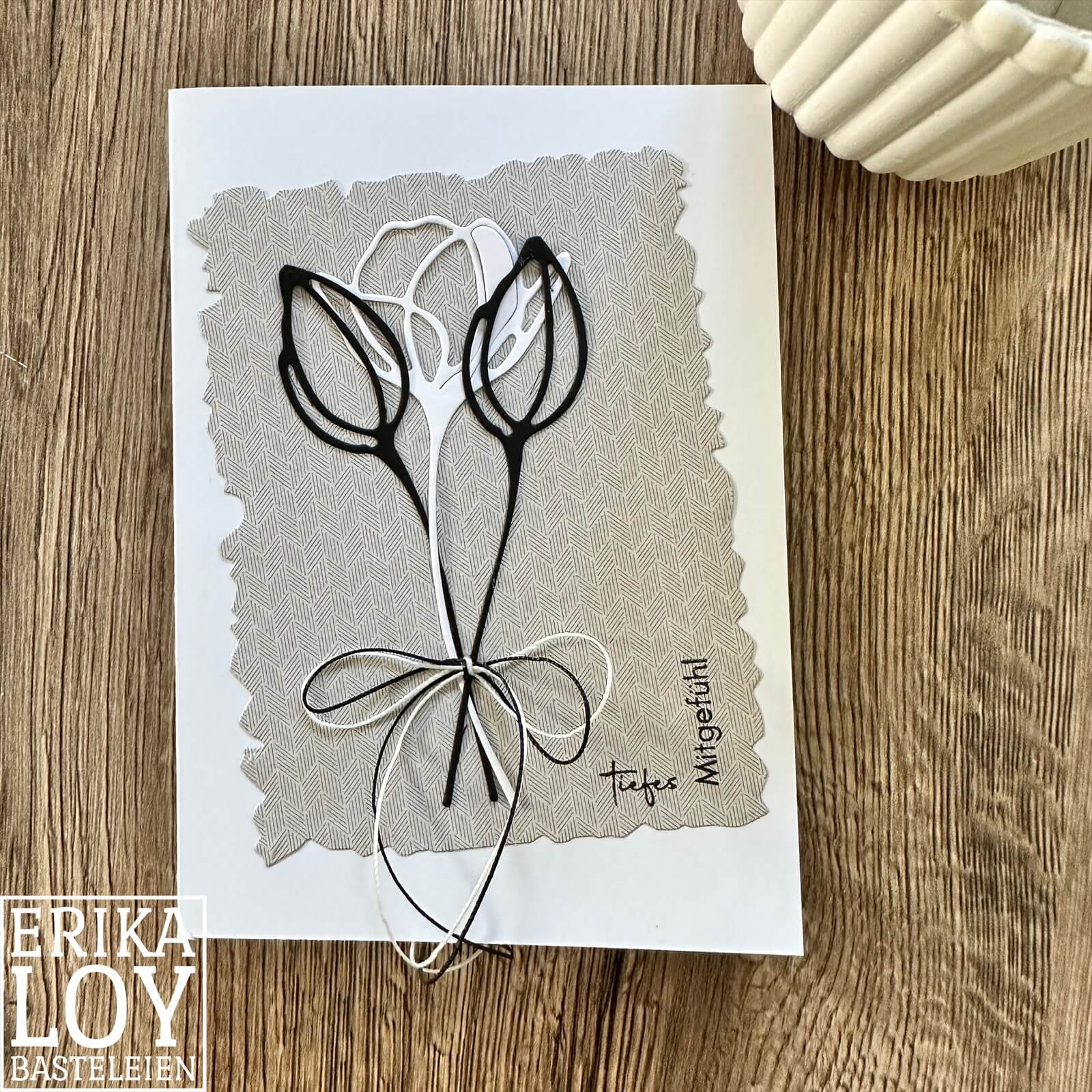 Eine handgefertigte Grußkarte mit minimalistischen schwarzen Blumenkonturen mit der "Stanzschablone Blume mit zwei Blüten" von Stanzenshop.de, mit gemustertem Hintergrund und "tiefem Mitgefühl", kompatibel mit der Stanze Big Shot.