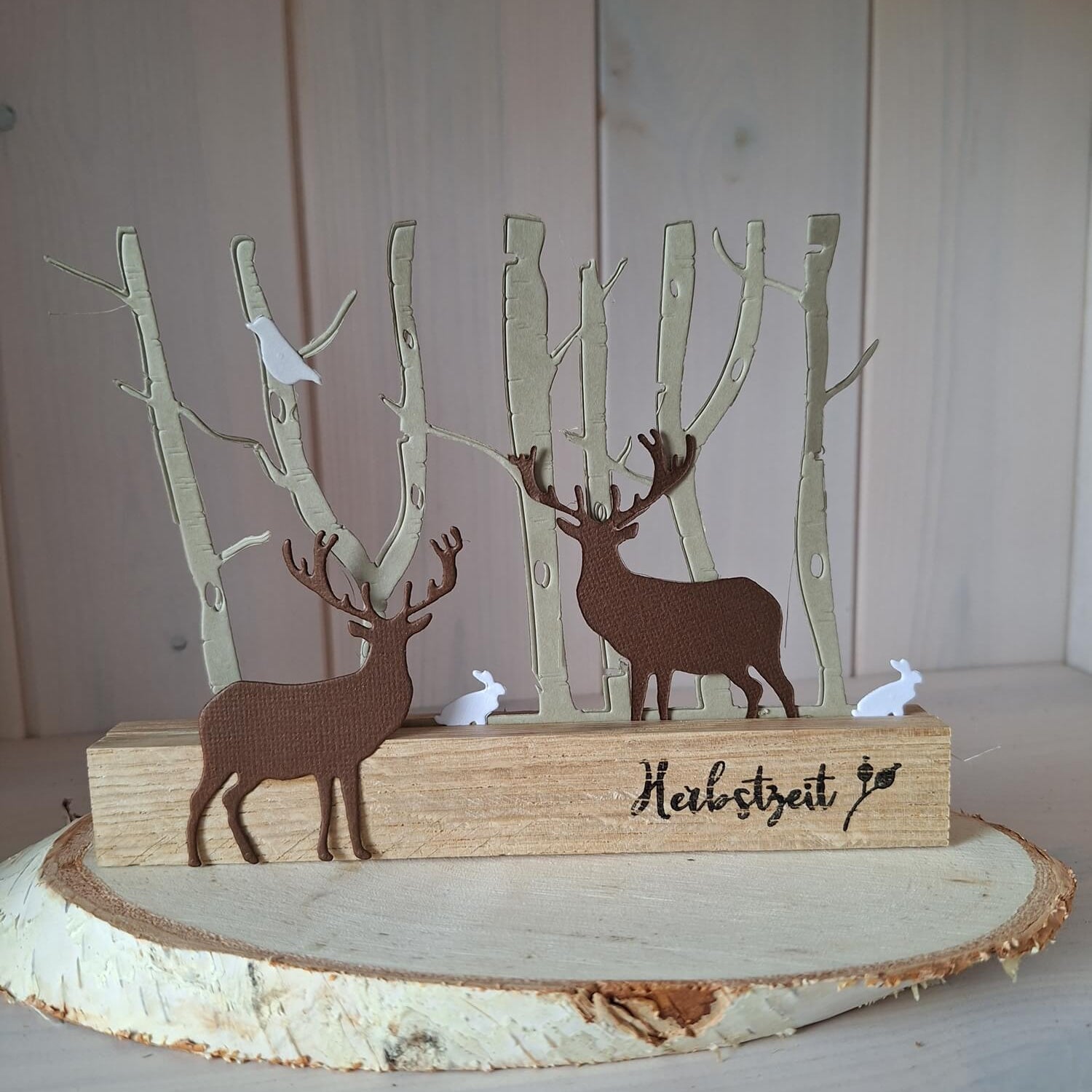 Ein hölzernes "Herbstzeit"-Ornament mit zwei Rehen, Bäumen, weißen Vögeln und Kaninchen auf einer runden Scheibe. Kompatibel mit der Stanzschablone von Stanzenshop.de: Einzelner Hirsch für Ihre Bastelprojekte.