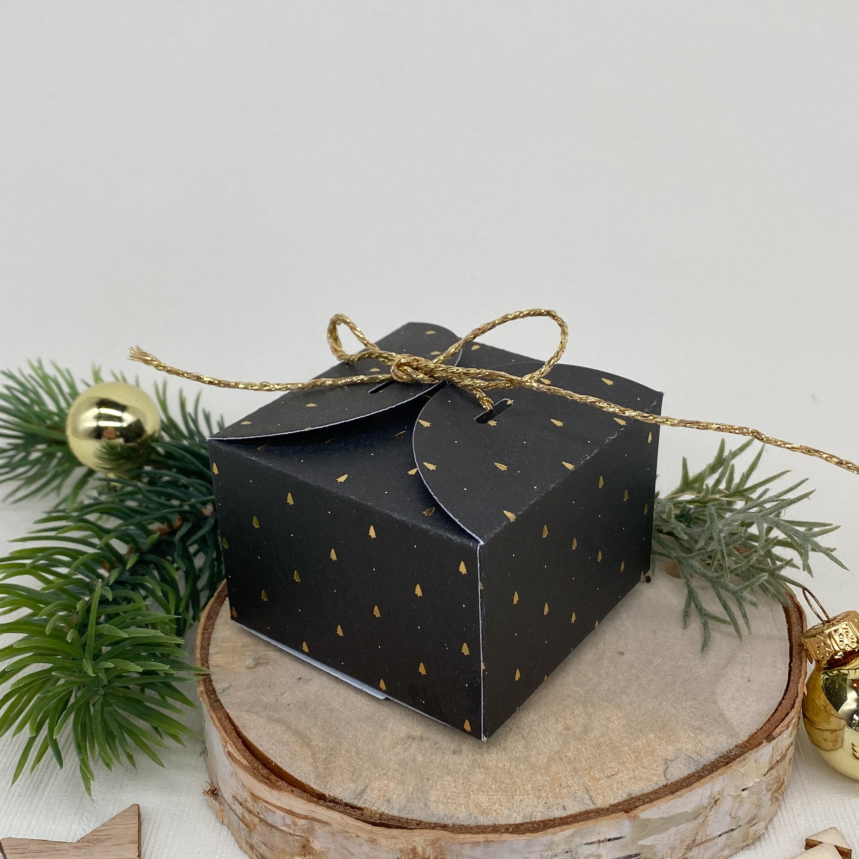 Die "Stanzschablone Quadratische Schachtel mit Verzierungen" von Stanzenshop.de zaubert eine festliche, schwarze Box mit Goldakzenten - ideal zum Basteln oder für kreative Geschenkideen in der Weihnachtszeit.