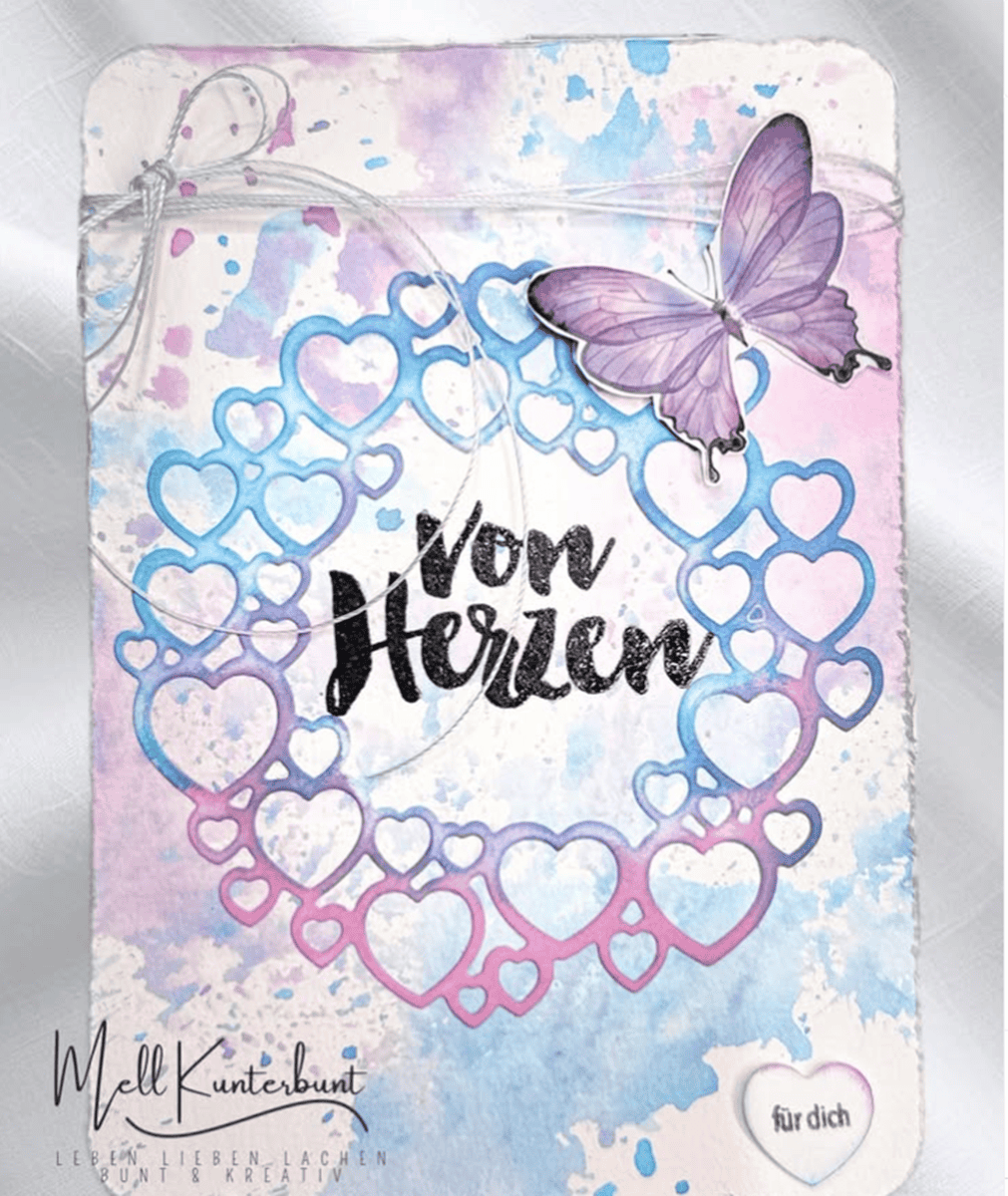 Eine pastellfarbene Karte mit Herzkranz und lilafarbenem Schmetterling, "Von Herzen" in Fettschrift, dazu "Für dich" auf einem kleinen Herz - gebastelt mit der Stanzschablone Kreis aus Herzen von Stanzenshop.de. Eine schöne Auswahl zum Basteln oder für Scrapbooking-Projekte.