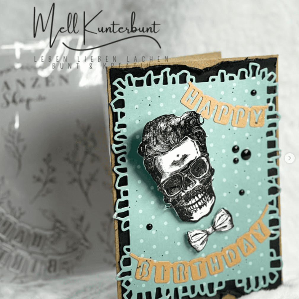 Für die handgefertigte Geburtstagskarte wurde die Stanzschablone Wimpelkette Happy Birthday von Stanzenshop.de verwendet. Sie zeigt einen Totenkopf mit gestyltem Haar und Fliege auf blauem Hintergrund, mit aufwendigen Cut-Outs und festlichen "Happy Birthday"-Akzenten.