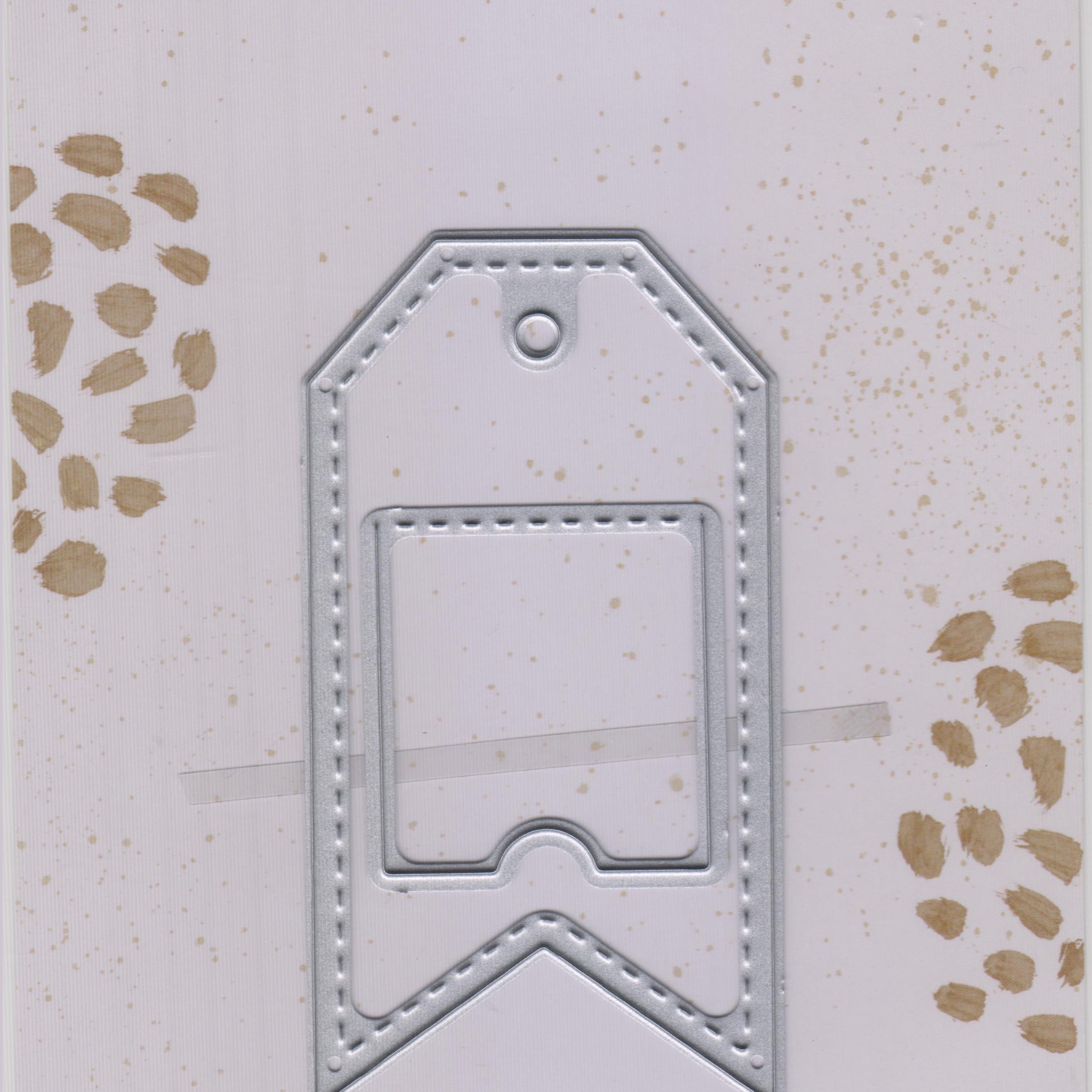 Eine silberne Stanzschablone aus Metall: Anhänger mit quadratischer Klappe gestanzt, abgebildet in Markenverpackung von Stanzenshop.de.