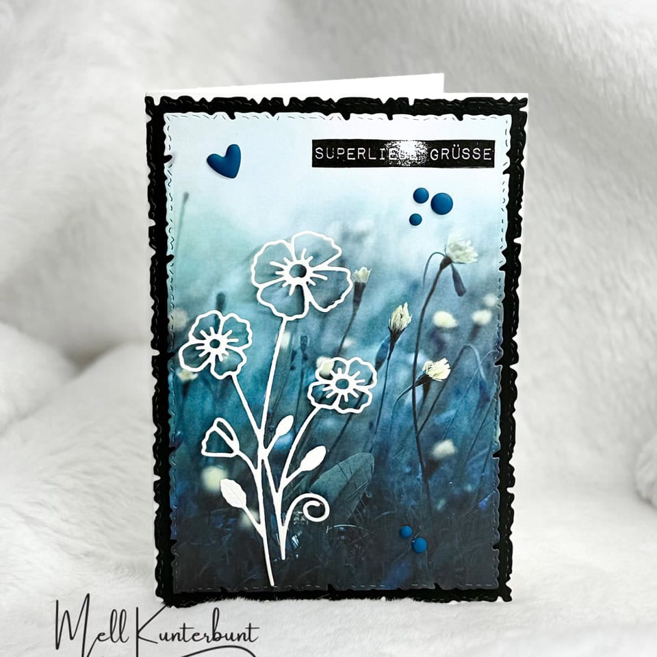 Eine handgefertigte Grußkarte mit blauem Blumenhintergrund, weißen Blumenkonturen aus Stanzschablone Blume mit drei Blüten von Stanzenshop.de, blauen Herzakzenten und "Super liebe Grüße" - ideal zum kreativen Basteln.