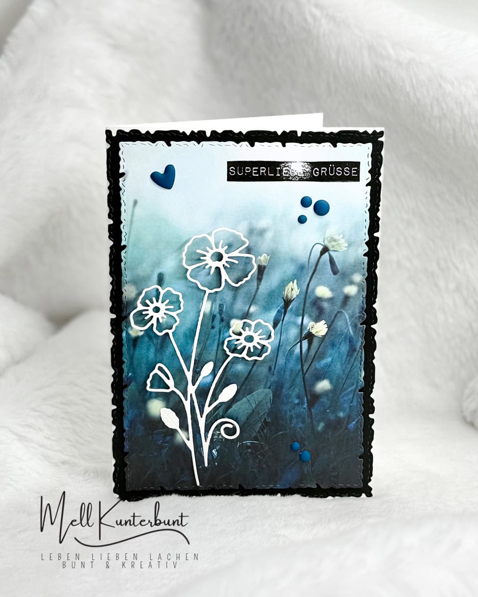 Eine handgefertigte Grußkarte mit blauem Blumenhintergrund, weißen Blumenkonturen aus Stanzschablone Blume mit drei Blüten von Stanzenshop.de, blauen Herzakzenten und "Super liebe Grüße" - ideal zum kreativen Basteln.