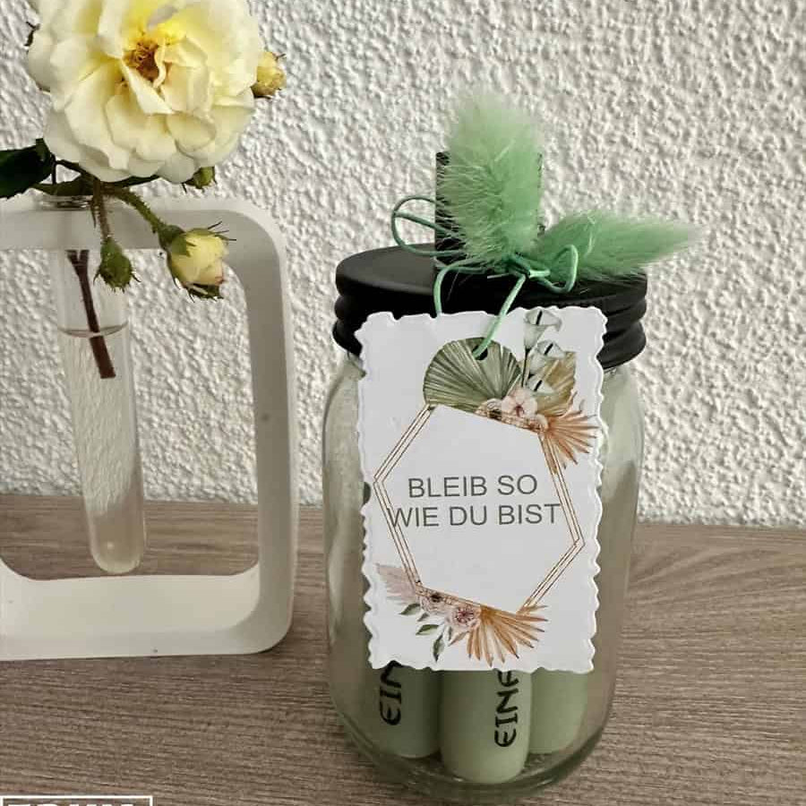 Die Stanzschablone "Sechs gewellte Rahmen in verschiedenen Größen" von Stanzenshop.de liegt neben einer weißen Vase mit gelber Blume-ideal zum Basteln oder Scrapbooking vor einer strukturierten weißen Wand.