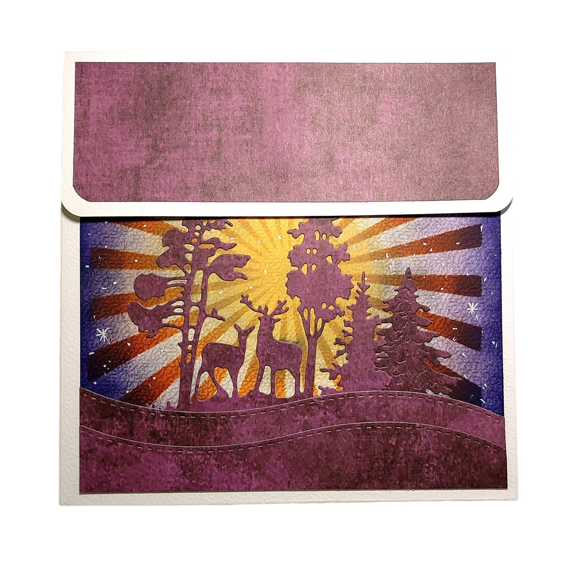 Eine Grußkarte mit einer lila-gelben Waldszene mit Rehen, Bäumen und einem Sonnenaufgang - perfekt für Basteln Karten oder in Kombination mit der Stanzschablone: Winterlandschaft im Halbkreis von Stanzenshop.de.