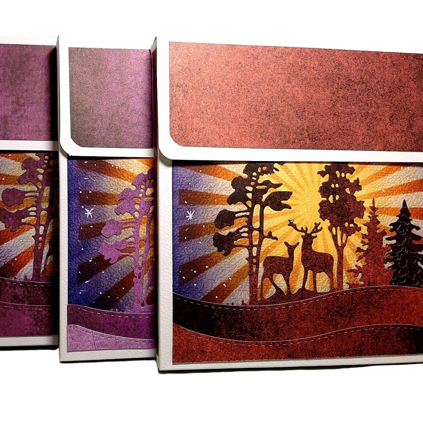 Drei rechteckige Dosen mit Deckel zeigen eine lebendige Waldszene mit Reh und Sonnenuntergang, ideal zum Basteln von Karten oder zur Ergänzung Ihrer Stanzenshop.de Stanzschablone: Winterlandschaft im Halbkreis gestaltet.