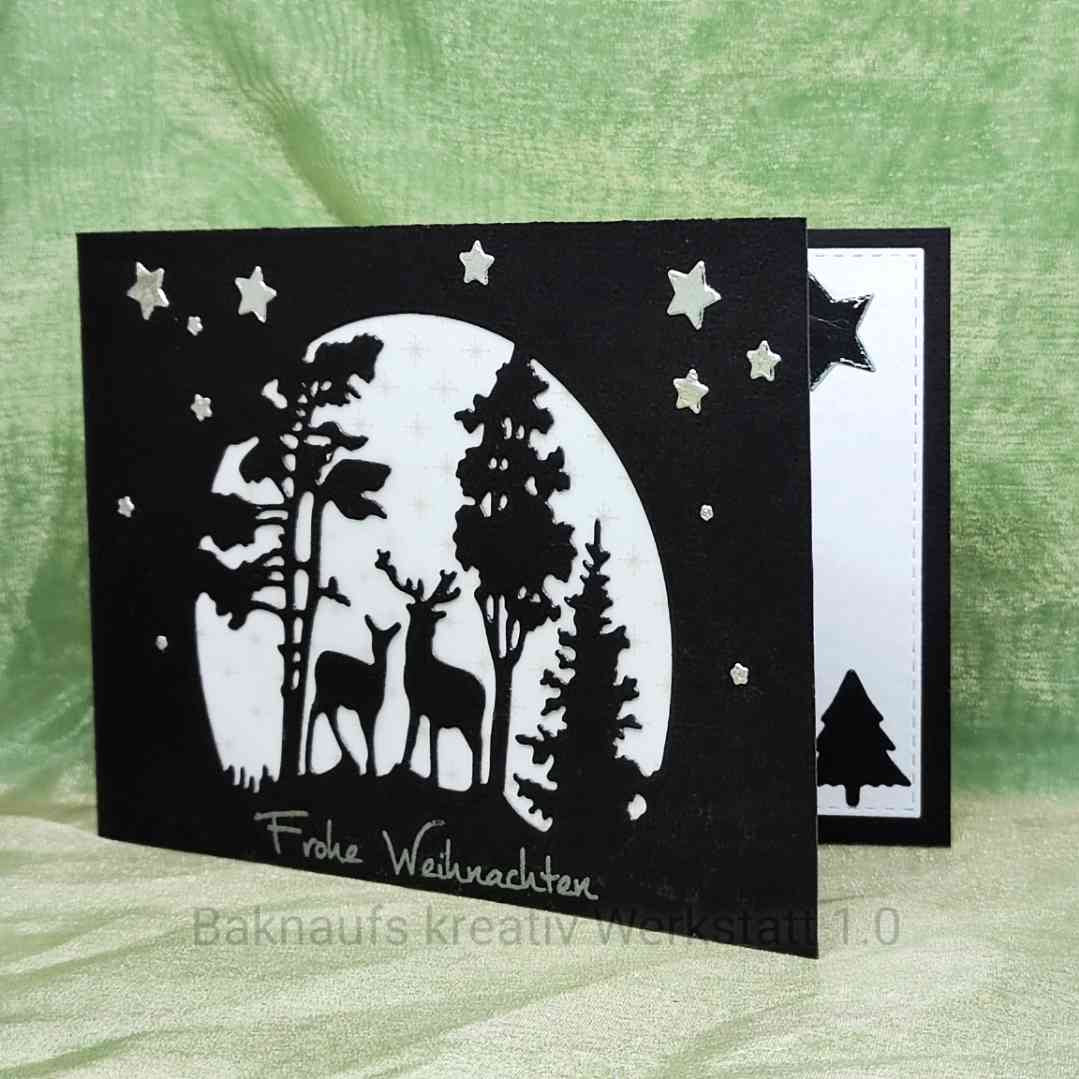 Schwarz-weiße Weihnachtskarte mit "Frohe Weihnachten" mit Waldszene, zwei Rehen, Sternen und Stanzschablone: Winterlandschaft im Halbkreis von Stanzenshop.de. Die Innenseite zeigt einen schwarzen Stern und eine Baumsilhouette.