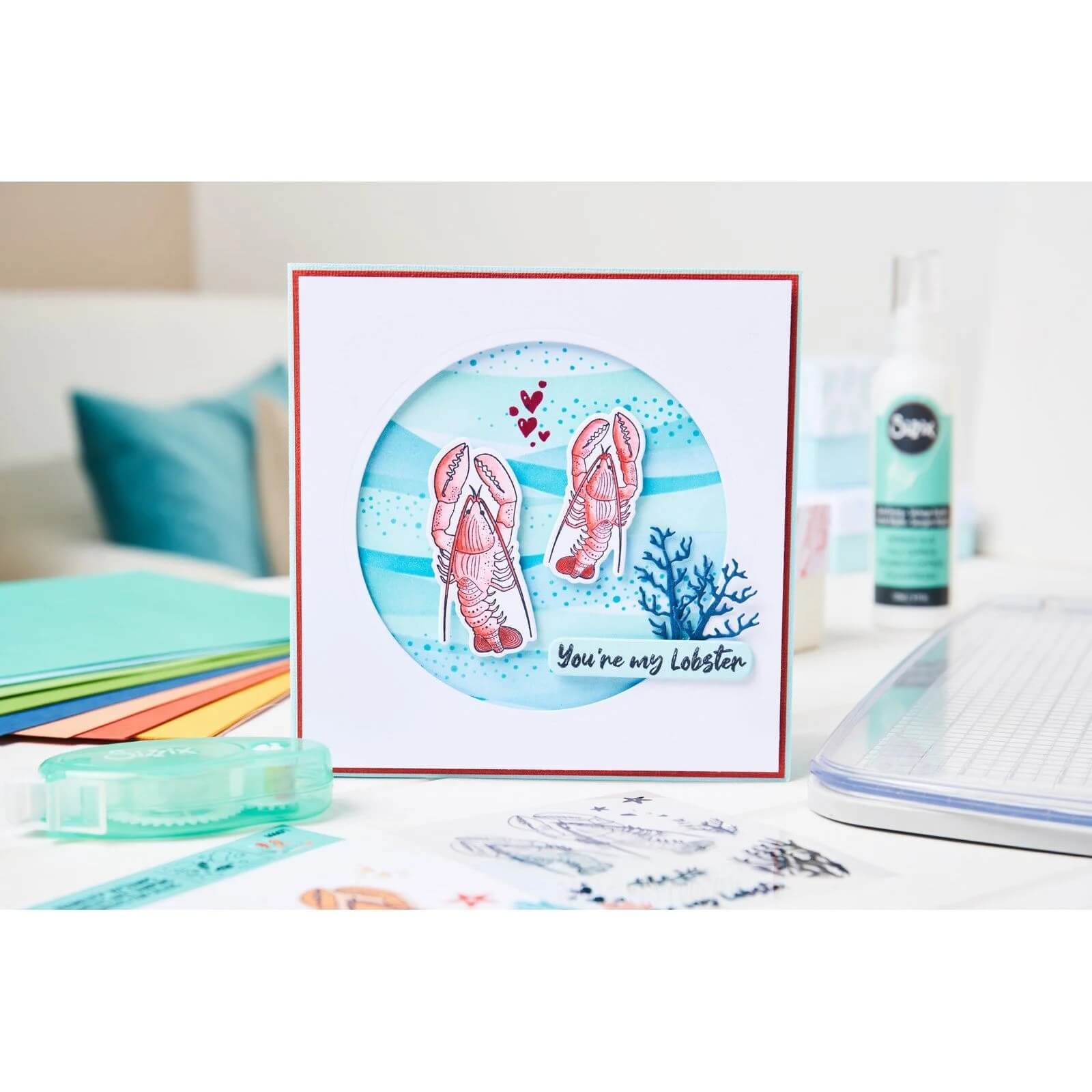 Eine handgefertigte Karte mit zwei illustrierten Hummern, Herzen, Seetang und "Du bist mein Hummer", erstellt mit dem Sizzix 666671 Framelits Stanzenset mit Stempeln You're my Lobster 24pcs von Sizzix, ausgestellt mit Bastelmaterial.