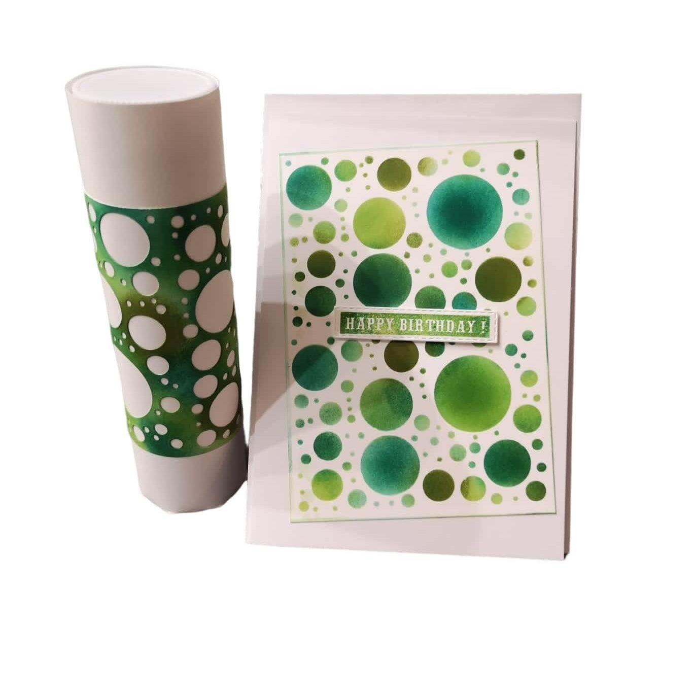 Auf weißem Hintergrund stehen eine weiße Tasse und eine Geburtstagskarte, beide mit grünen und weißen Punkten, die mit der Stanzschablone Platte mit Kreisen von Stanzenshop.de hergestellt wurden.