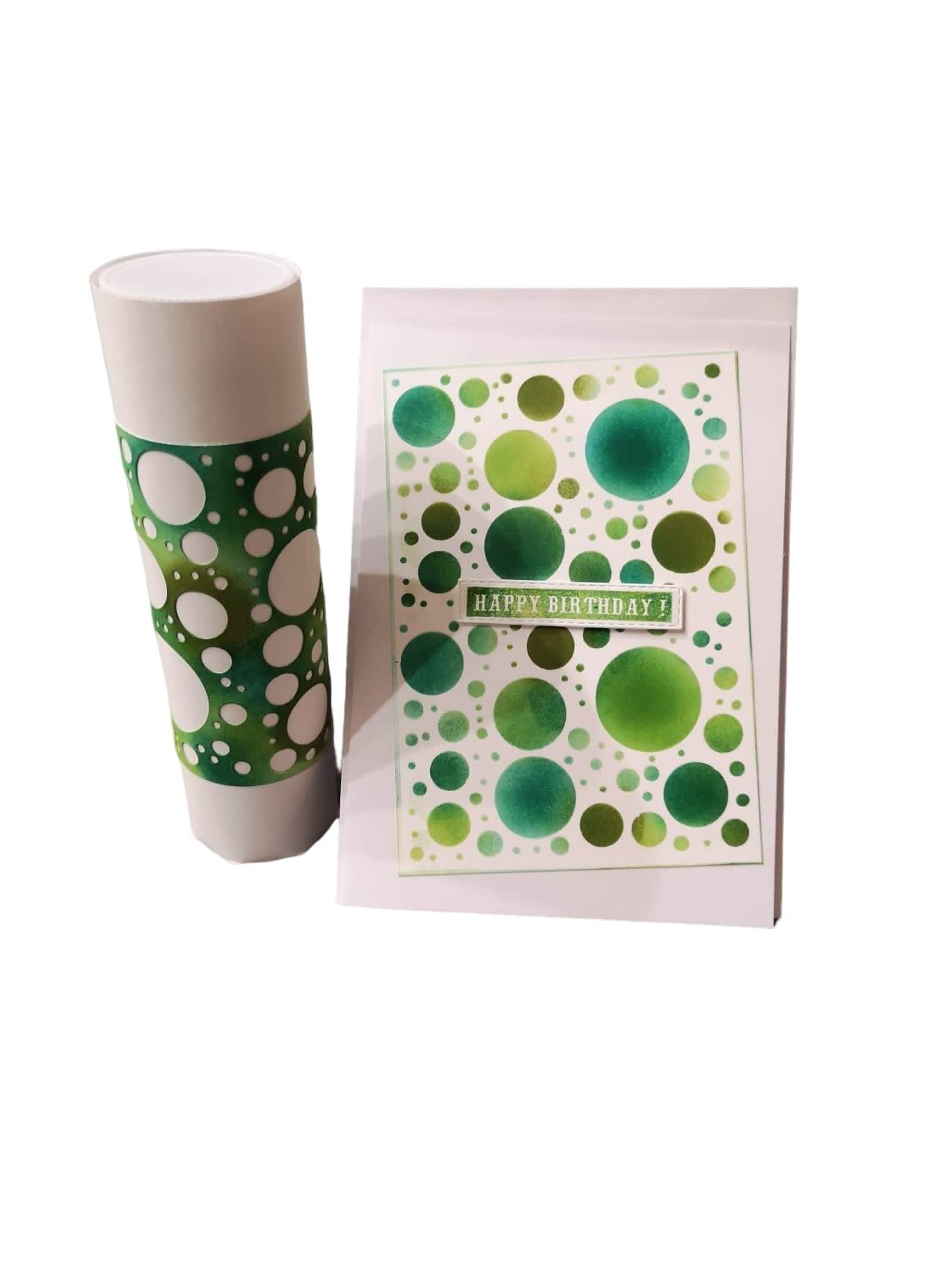 Auf weißem Hintergrund stehen eine weiße Tasse und eine Geburtstagskarte, beide mit grünen und weißen Punkten, die mit der Stanzschablone Platte mit Kreisen von Stanzenshop.de hergestellt wurden.