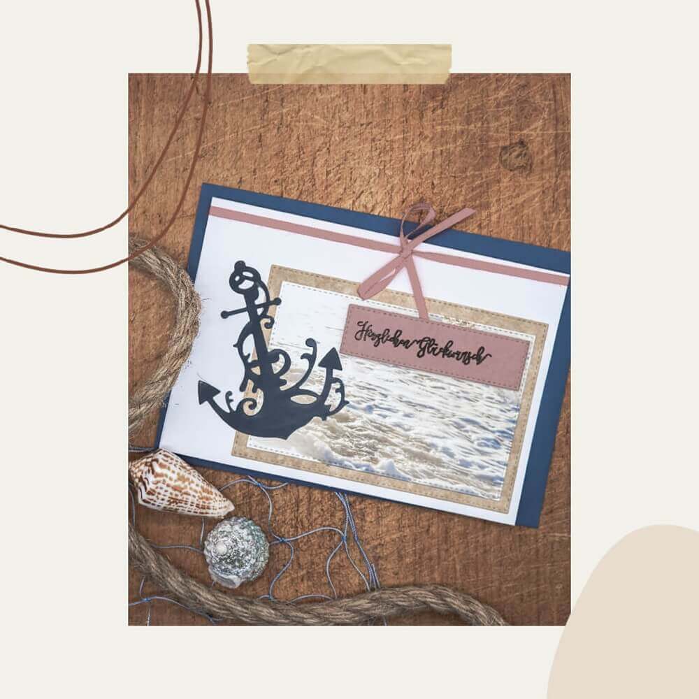 Die "Stanzschablone Anker mit Verschnörkelung" von Stanzenshop.de gestaltet eine maritime Grußkarte mit Ankerausschnitt, Tau, Muschel, Wellenfoto und "Herzlichen Glückwunsch" - ideal für Scrapbooking.