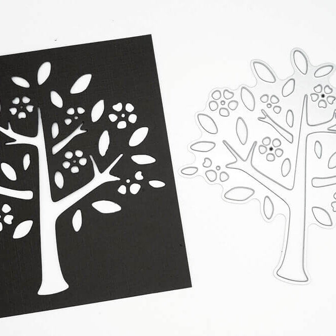 Die Stanzschablone "Baum mit Blüten und Blättern" von Stanzenshop.de liegt neben einem schwarzen Papier-Ausschnitt des Designs - ideal für Bastel- und Scrapbooking-Projekte.
