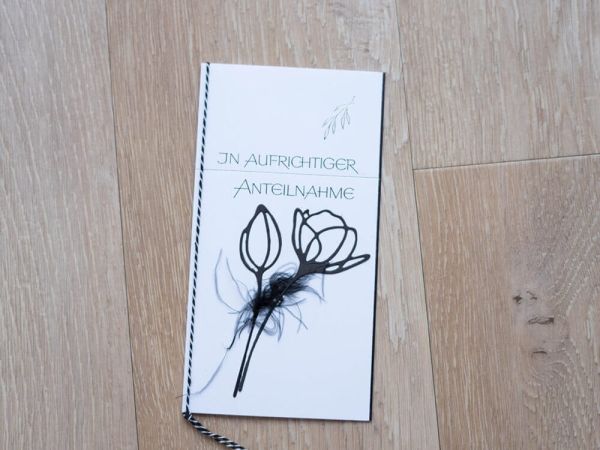 Eine deutsche Kondolenzkarte mit floralem Design, hergestellt mit der Stanzenshop.de Stanzschablone Blume mit zwei Blüten die, ruht auf Holz. Auf der Karte steht "In aufrichtiger Anteilnahme" in grüner Schrift.