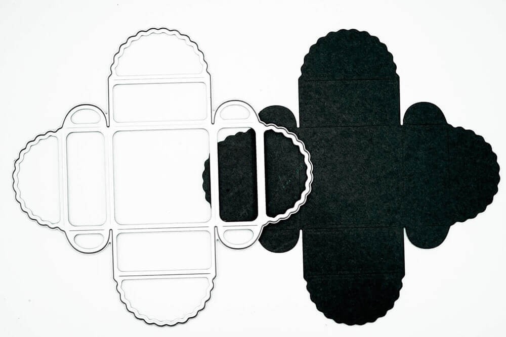 Das Stanzschablone Geschenkkästchen von Stanzenshop.de und sein schwarzer Papierausschnitt für eine Wellenkantenschachtel werden auf weißem Hintergrund gezeigt - ideal für Scrapbooking oder Basteln.