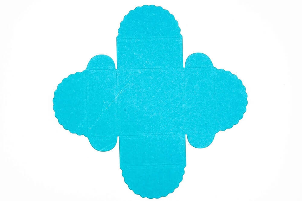 Stanzschablone Geschenkkästchen von Stanzenshop.de: Flacher, ungefalteter blauer Karton mit gewelltem Rand, ideal zum Basteln oder Scrapbooking, auf weißem Hintergrund.