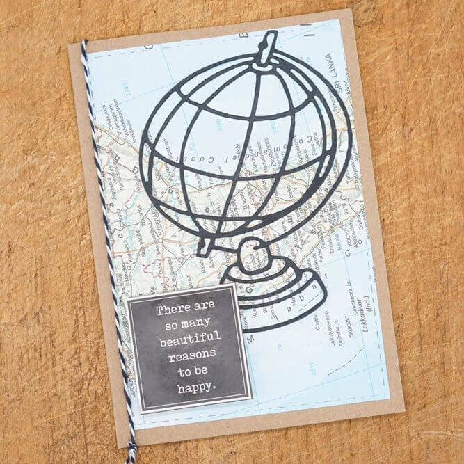 Diese handgefertigte Karte verwendet die Stanzschablone: Großer Globus von Stanzenshop.de, um einen schwarzen Drahtgitter-Globus über einem Kartenhintergrund mit der Botschaft zu zeigen: "Es gibt so viele schöne Gründe, glücklich zu sein.