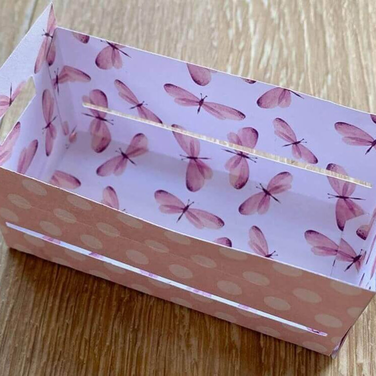 Eine kleine rechteckige Geschenkbox Hochzeit, hergestellt mit der "Stanzschablone: Großer Karton" von Stanzenshop.de mit rosa Libellen- und Tupfenmuster auf einer Holzunterlage.