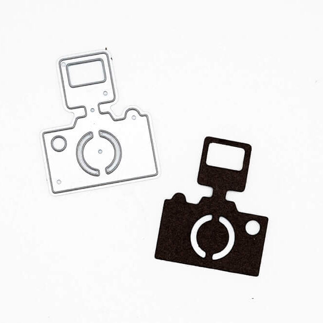 Die "Stanzschablone: Kamera mit Blitz" von Stanzenshop.de und ihr schwarzer Papierausschnitt werden auf weißem Grund dargestellt - ideal für Scrapbooking- oder Cardmaking-Projekte.