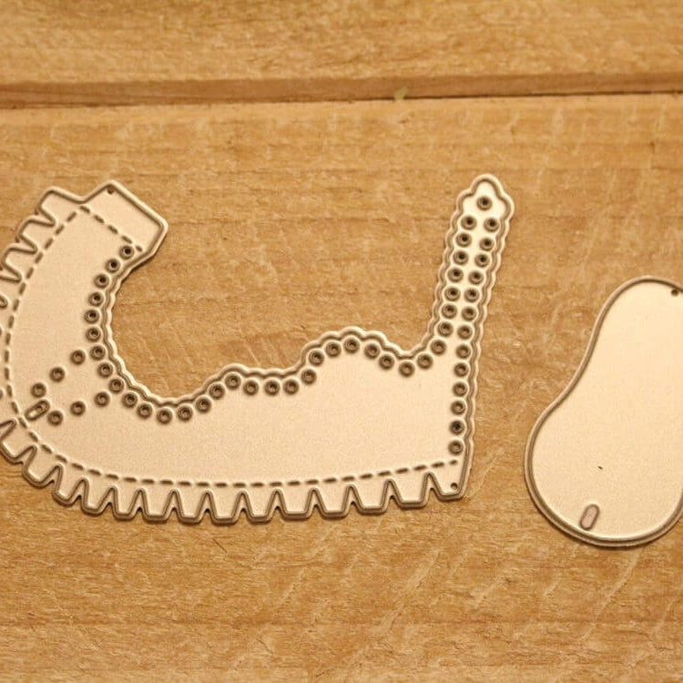 Die Stanzschablone Kinderschuh für ein Baby von Stanzenshop.de besteht aus einem Latzstempel mit Wellenschliff und einem kleinen Bohnenstempel, abgebildet auf einer Holzfläche - ideal für Scrapbooking.