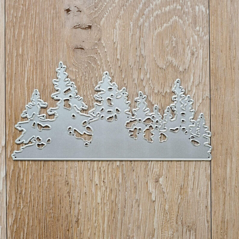 Die "Stanzschablone: Landschaft aus Tannenbäumen" von Stanzenshop.de liegt auf einem Holzuntergrund, ideal für Basteln Winter oder Stanzschablone Weihnachten Projekte.