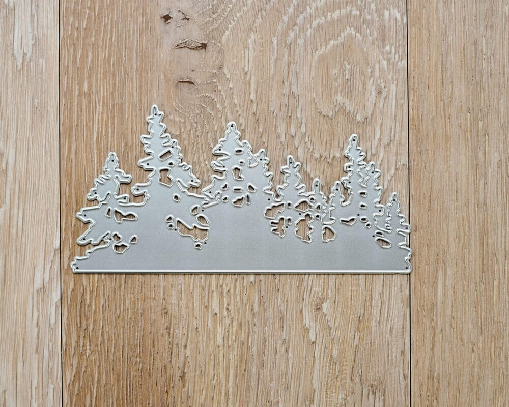 Die "Stanzschablone: Landschaft aus Tannenbäumen" von Stanzenshop.de liegt auf einem Holzuntergrund, ideal für Basteln Winter oder Stanzschablone Weihnachten Projekte.