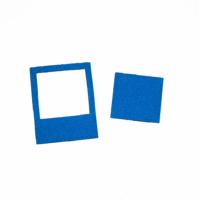 Eine blaue "Stanzschablone Rahmen für Polaroidbild" von Stanzenshop.de mit einem ausgeschnittenen Zentrum sitzt neben einem einfarbig blauen Quadrat - ideal für Scrapbooking oder Basteln mit Ihrer Lieblingsstanze auf weißem Hintergrund.