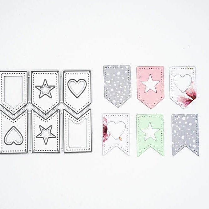 Die Stanzschablone Sechs Anhänger von Stanzenshop.de enthält sechs gestanzte Anhänger, ideal für Scrapbooking oder Basteln, mit Stern- und Herzausschnitten in Schwarz, Weiß, Grau, Rosa und Grün - in zwei Reihen auf weißem Hintergrund.