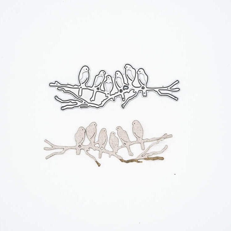 Zwei Metallausschnitte - ein silberner und ein goldener - zeigen sechs Vögel auf einem Zweig. Ideal für die "Stanzschablone: Sechs Vögel auf einem Ast" von Stanzenshop.de für Scrapbooking oder Kartenherstellung Projekte. Dargestellt auf einem schlichten weißen Hintergrund.
