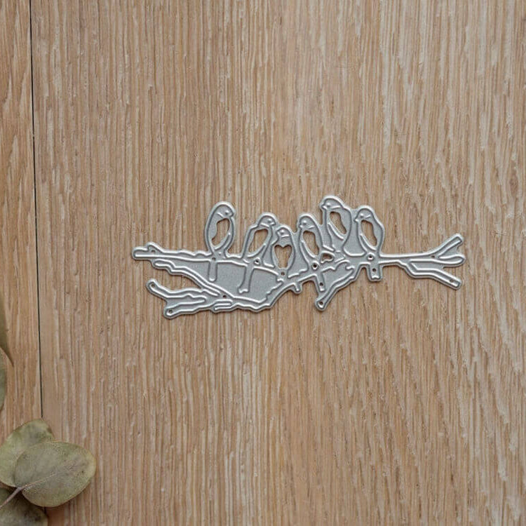 Die Stanzenshop.de "Stanzschablone: Sechs Vögel auf einem Ast" ist eine Stanze auf Holz mit getrockneten Blättern - ideal für Scrapbooking oder Kartenherstellung.