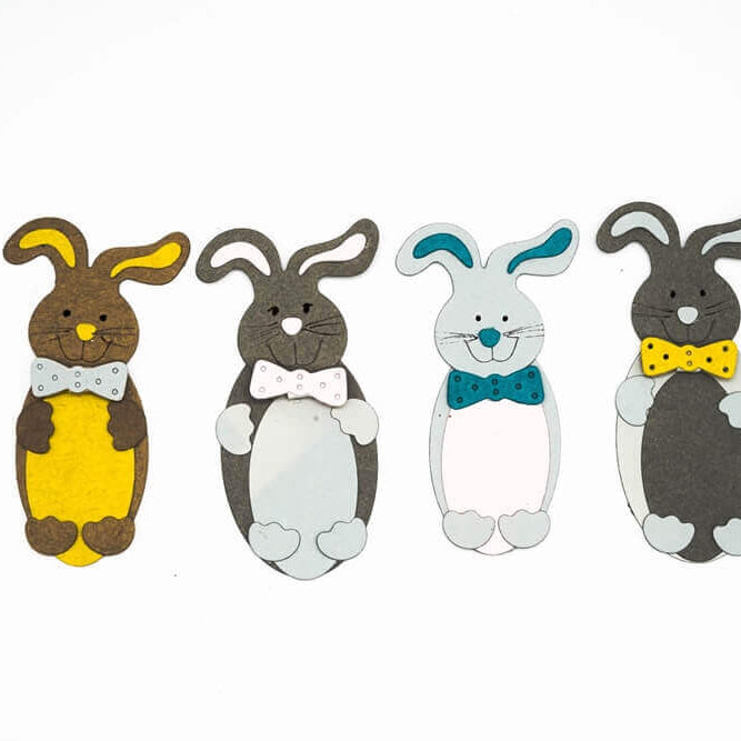 Vier Papierausschnitte von Cartoon-Hasen mit Fliege, die in einer Reihe angeordnet sind - perfekt für Osterbasteleien mit der "Stanzschablone: Süßer Osterhase" von Stanzenshop.de.