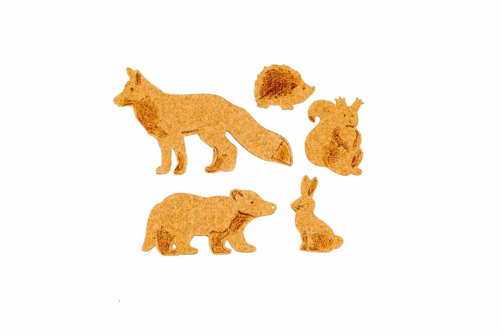 Fünf Korkausschnitte von Waldtieren - Fuchs, Igel, Hase, Eichhörnchen und Dachs - sind auf einem weißen Hintergrund angeordnet. Ideal für Bastelideen mit dem Stanzschablonen-Set für Waldtiere von Stanzenshop.de.