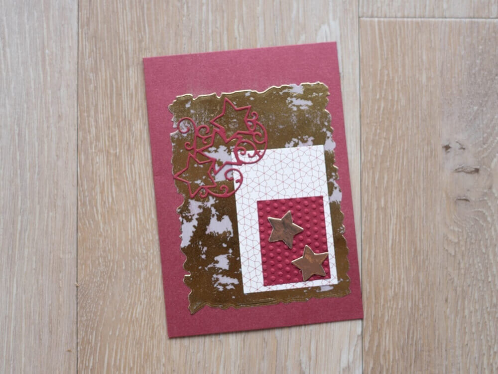 Die Stanzschablone "Sechs gewellte Rahmen in verschiedenen Größen" von Stanzenshop.de verleiht Grußkarten mit gold-pinken Sternen auf rotem Hintergrund einen einzigartigen Look - ideal für Scrapbooking oder Basteln.