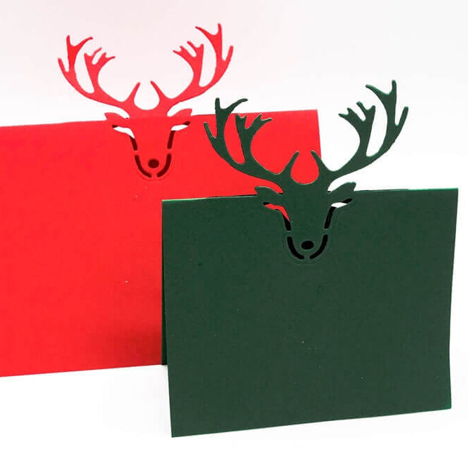 Die Stanzschablone: Tischkarte Rentierkopf von Stanzenshop.de zaubert rote und grüne Klappkarten mit einem Rentierkopf-Ausschnitt - ideal für Tischkarten basteln oder kreative Scrapbooking-Projekte.