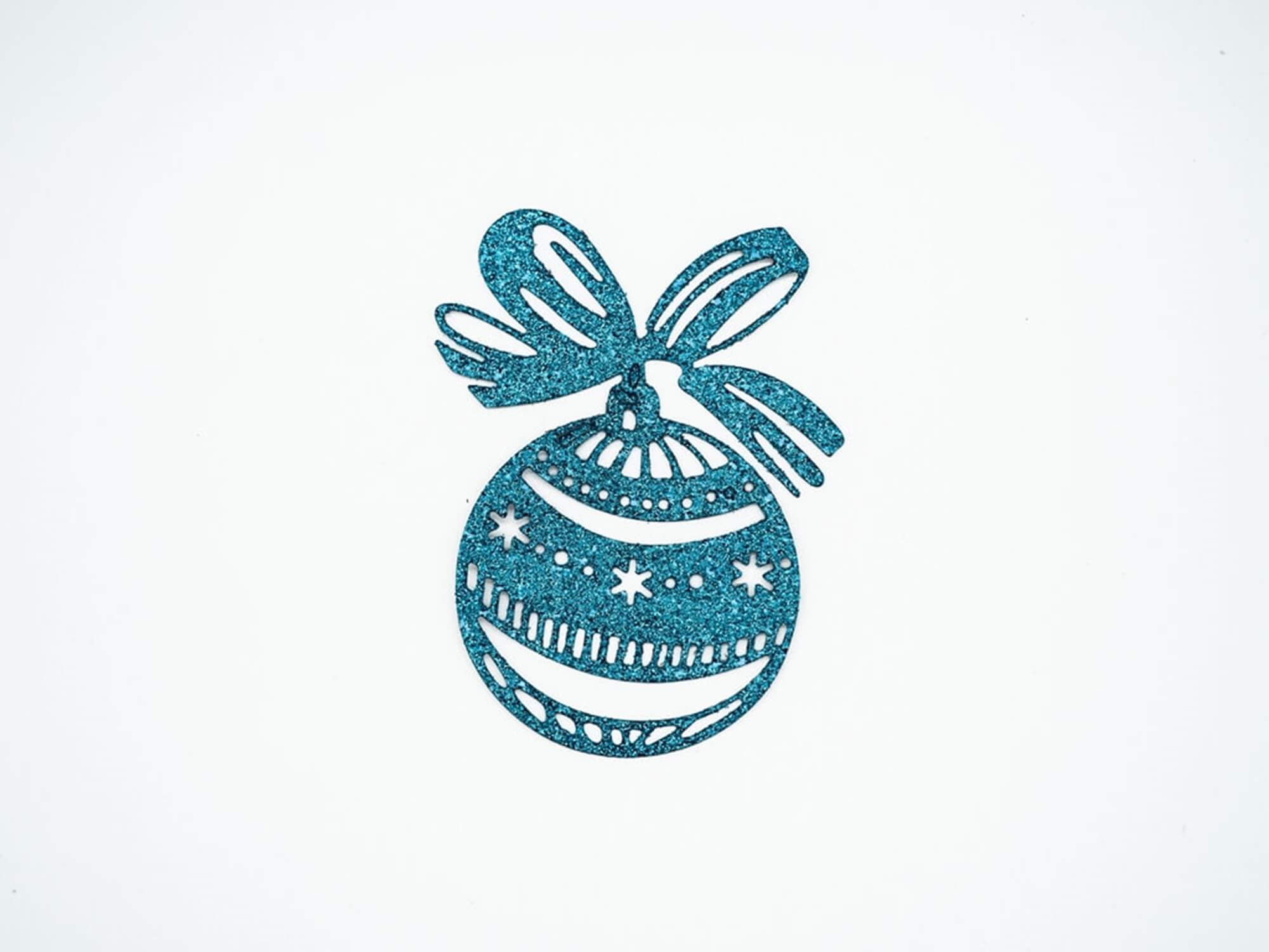 Die "Stanzschablone Weihnachtskugel mit Schleife" von Stanzenshop.de ist eine blaue glitzernde Ornamentausstanzung mit Sternen und Wirbeln, ideal für Basteln Winterprojekte, dargestellt auf einem schlichten weißen Hintergrund.