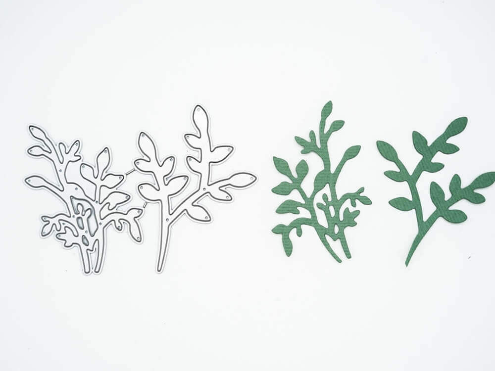 Auf der linken Seite sind zwei Metallstempel "Stanzschablone: Zwei Eukalyptus Sträuche" von Stanzenshop.de und auf der rechten Seite passende grüne Stanzteile, die sich perfekt für Scrapbooking oder Basteln eignen, alles auf weißem Hintergrund.