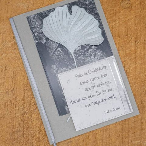 Eine Kondolenzkarte verziert mit der Stanzenshop.de Stanzschablone Zwei Ginkgoblätter und einem Goethe-Zitat auf der Vorderseite, platziert auf Holz - ideal zum Basteln oder für Scrapbooking-Projekte.