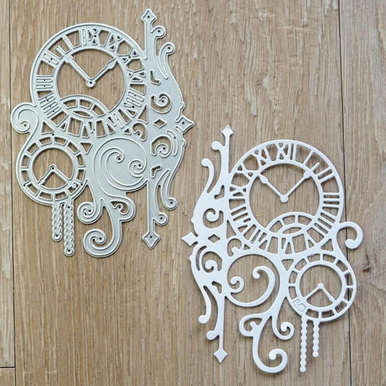 Die "Stanzeschablone Zwei Uhren mit Ranken" von Stanzenshop.de bietet zwei verschnörkelte Ziffernblattausschnitte aus Metall mit römischen Ziffern, ideal um Scrapbooking- oder Bastelprojekte mit Vintage-Details zu versehen.