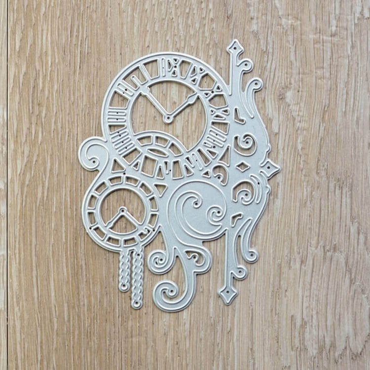 Die Stanzschablone Zwei Uhren mit Ranken von Stanzenshop.de zeigt filigrane Ziffernblätter und Wirbel, die sich ideal für Scrapbooking eignen und elegant auf einer hellen Holzoberfläche präsentiert werden.