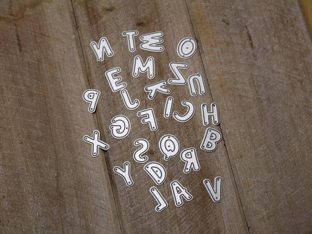 Eine Gruppe von Stanzschablonen: Buchstaben A -Z, gerade Buchstaben auf einer Holzoberfläche der Marke Stanzenshop.de.