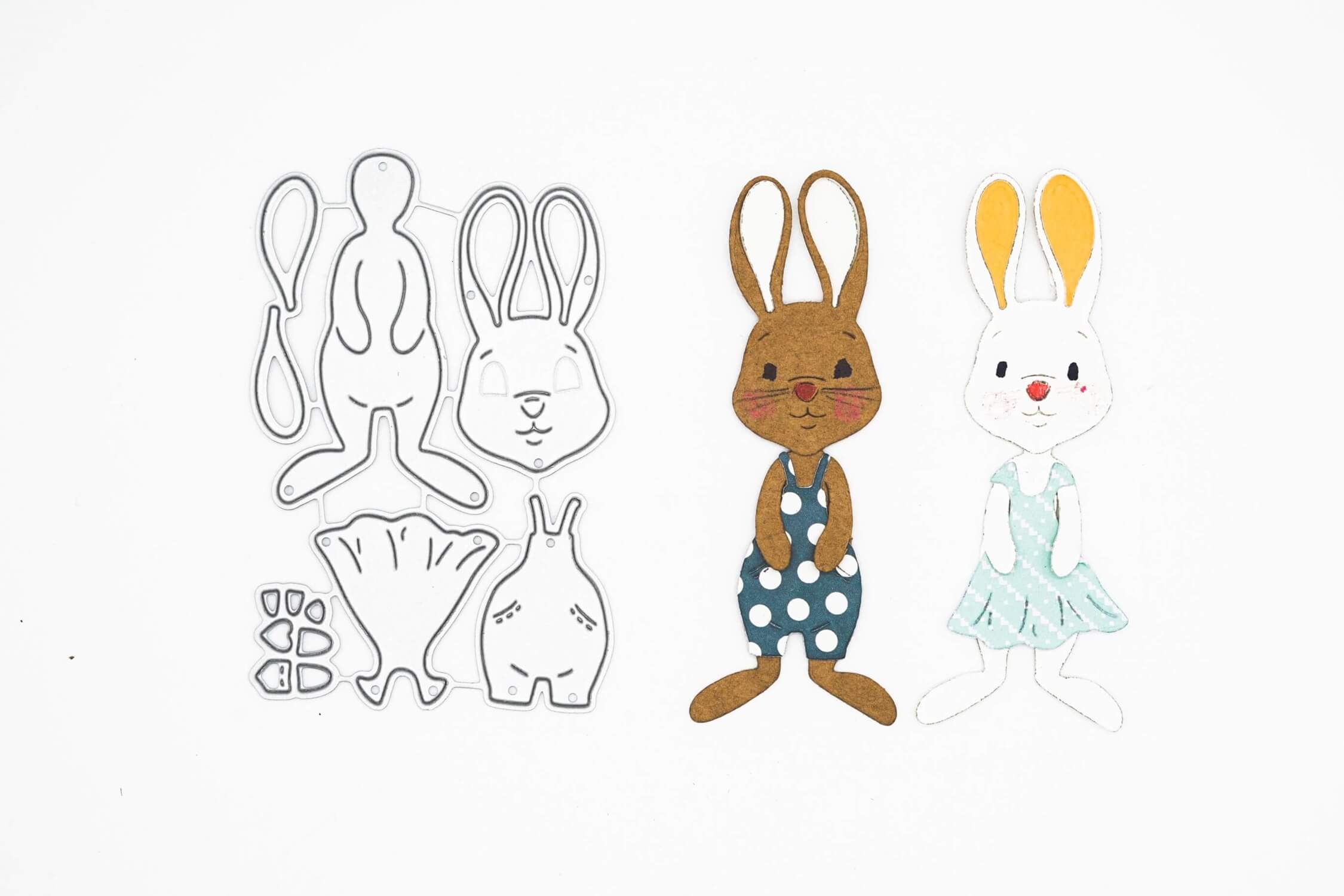 Die Stanzschablone: Bastelset Osterhase von Stanzenshop.de enthält Stanzformen in Hasenform aus Metall und zwei zusammengesetzte Papierhasen - braun mit gepunktetem Kleid und weiß mit blauem Kleid - ideal für Scrapbooking, dargestellt auf weißem Hintergrund.