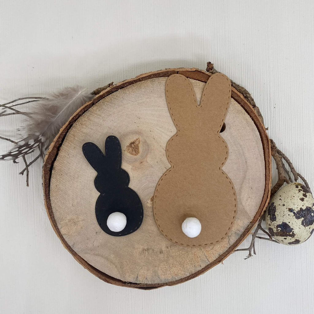 Holzscheibe mit zwei Hasen-Silhouetten, dekorativen Eiern und einem Stanzschablonen-Design, perfekt für Scrapbooking von Stanzenshop.de.
