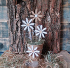 Die Stanzschablone: Blumenblüte von Stanzenshop.de zeigt zarte weiße und beigefarbene Gänseblümchenmotive, ideal zum Basteln oder für Scrapbooking-Projekte. Ausgestellt mit Heu auf Holzrinde für einen rustikalen Touch.