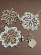 Die "Stanzschablone: Blatt mit Rahmen" von Stanzenshop.de zeigt Blattausschnitte mit Rahmen, ideal zum Basteln oder Scrapbooking, wunderschön in Szene gesetzt mit Holzakzenten auf einem braun gepunkteten Hintergrund.