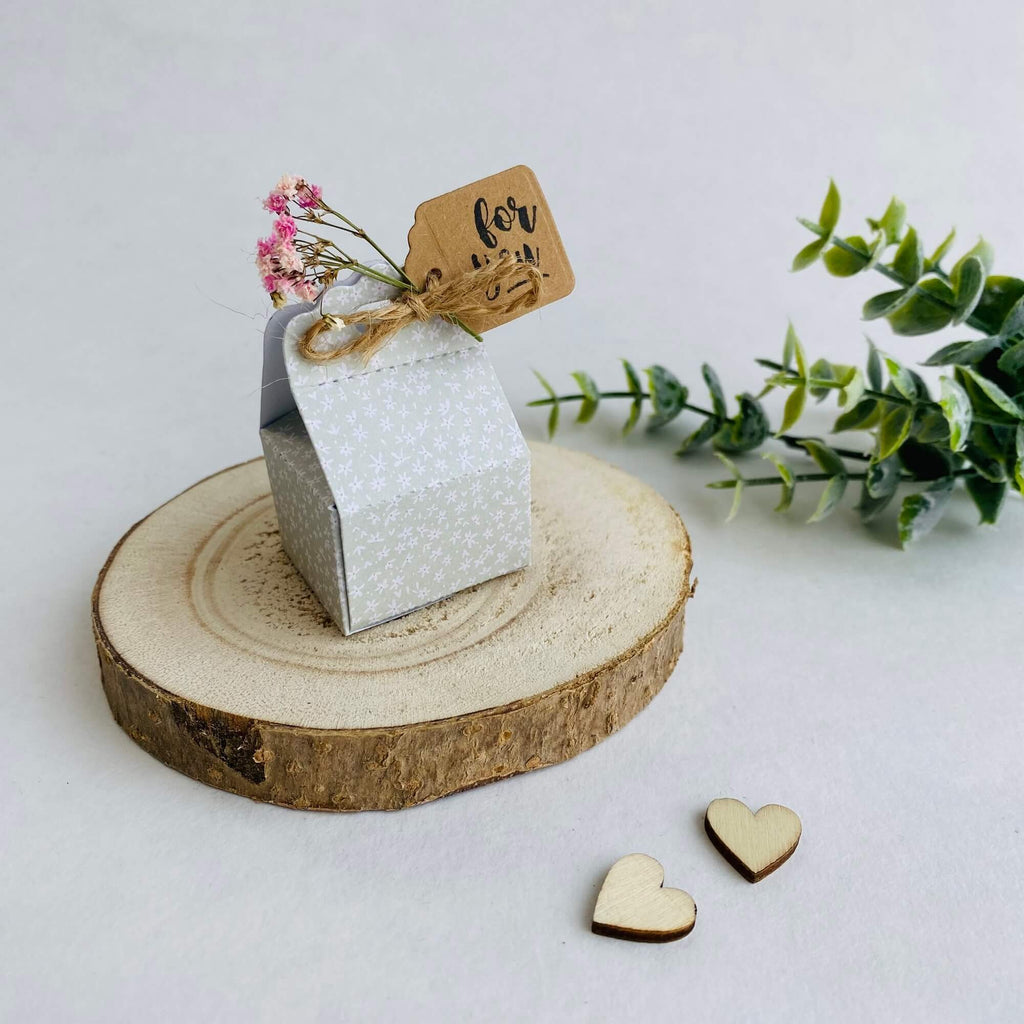Eine kleine Geschenkbox mit einem „Für Sie“-Tag auf einer rustikalen Holzscheibe, begleitet von dekorativen Herzen und Grün, perfekt für Scrapbooking aus der Stanzschablone Süße Schachtel von Stanzenshop.de.