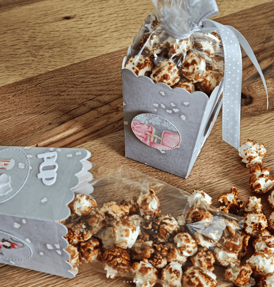 Zwei Karamell-Popcornschachteln - eine aufrecht mit Schleife, die andere Popcorn verschüttend - zeigen kreative Möglichkeiten, die Stanzschablone Popcornschachtel von Stanzenshop.de zu verwenden. Ideal als Gastgeschenke zur Hochzeit oder zum Basteln von Schachteln.