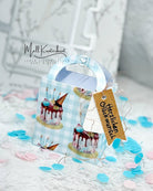 Die Stanzschablone Kleine Tasche von Stanzenshop.de fertigt eine kleine Tasche mit Kuchenmotiv und braunem "Herzlichen Glückwunsch"-Anhänger, umgeben von blau-pinkem Konfetti - ideal zum Basteln oder als Geschenkverpackung.