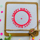 Die Stanzschablone Happy Birthday auf rundem Schriftzug" von Stanzenshop.de ist ideal für Scrapbooking oder Karten gestalten - gestalten Sie damit Karten mit einem rot eingekreisten Happy Birthday, Konfettipunkten, Schnur und einem "With Love"-Anhänger.